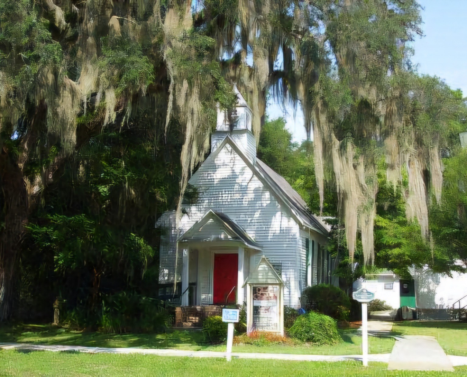 Historic white chapel with red doors and Spanish moss